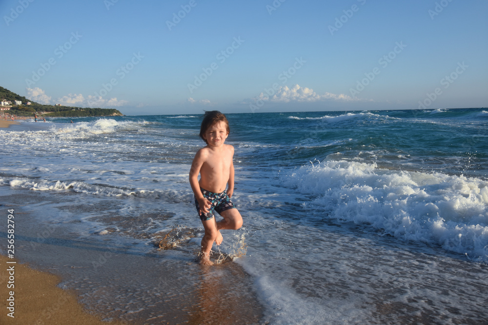 Child running and play at beach. Little boy play by the sea on summer vacation
