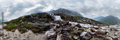 Mountain waterfall stream in misty rainy weather in the valley flowers. Cylindrical panorama 360