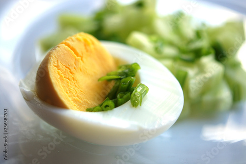 Half an egg with green onions, chopped egg, vegetable salad. Macro yellow yolk, white egg white, chopped onion. Useful breakfast, menu for restaurant, recipe book. Food on a transparent plate.