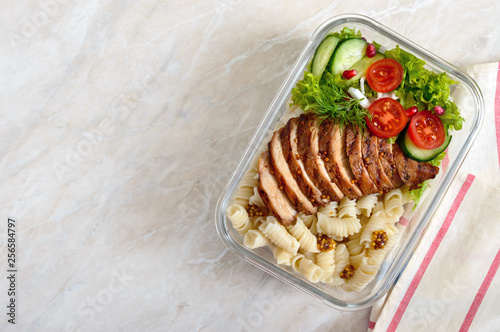 Lunch box: rotini with baked chicken breast and salad. Top view, flat lay. Delicious healthy lunch. The concept of healthy eating.