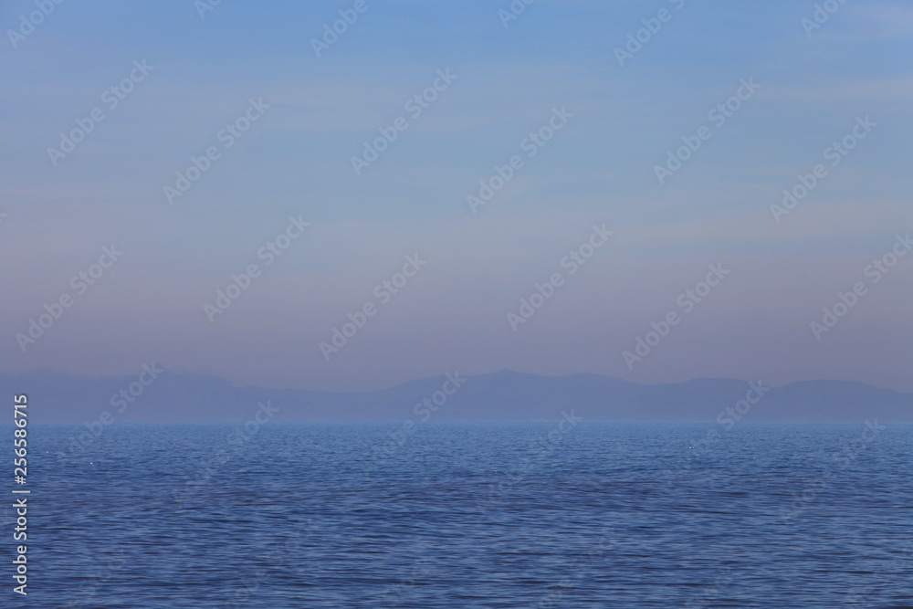 Fototapeta premium Simple seascape of hazy mountains on the horizon