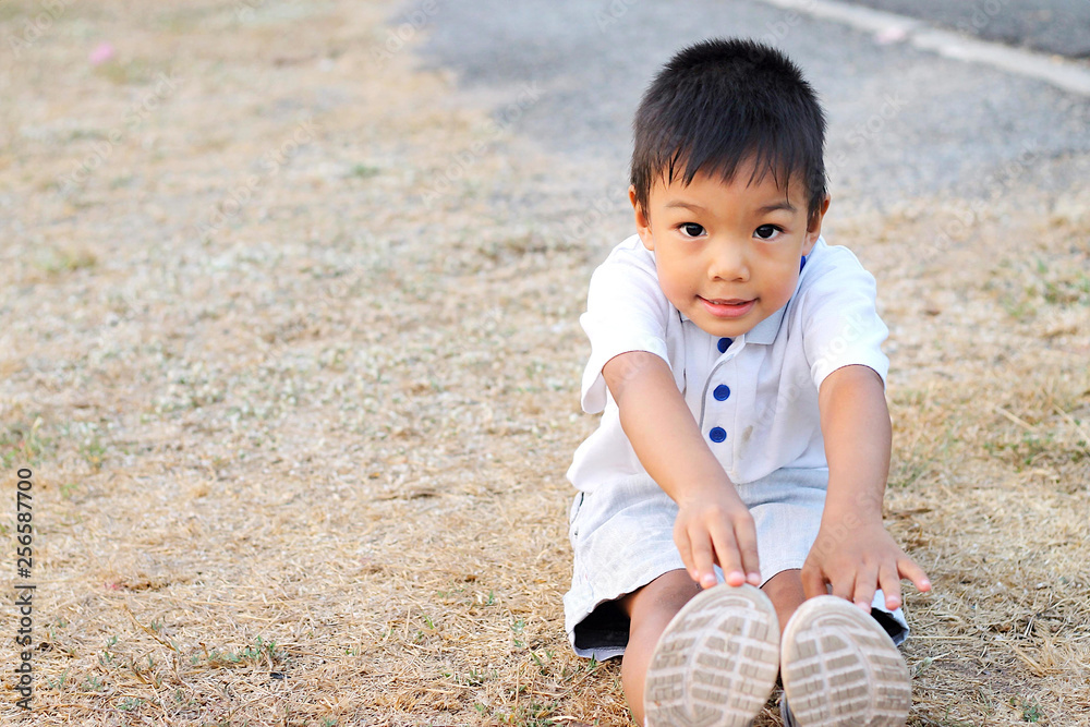 Kid and exercise for health concept. Happy Asian child boy warm up his body before he run and exercise. His hands touching floor. Kid and exercise for health concept. Happy Asian child boy warm up his body before he run and exercise. His hands touching floor.