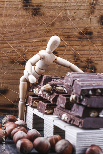 Czekolada ukladana na palecie przez drewnianego ludzika, lalke, magazyn czekolady.