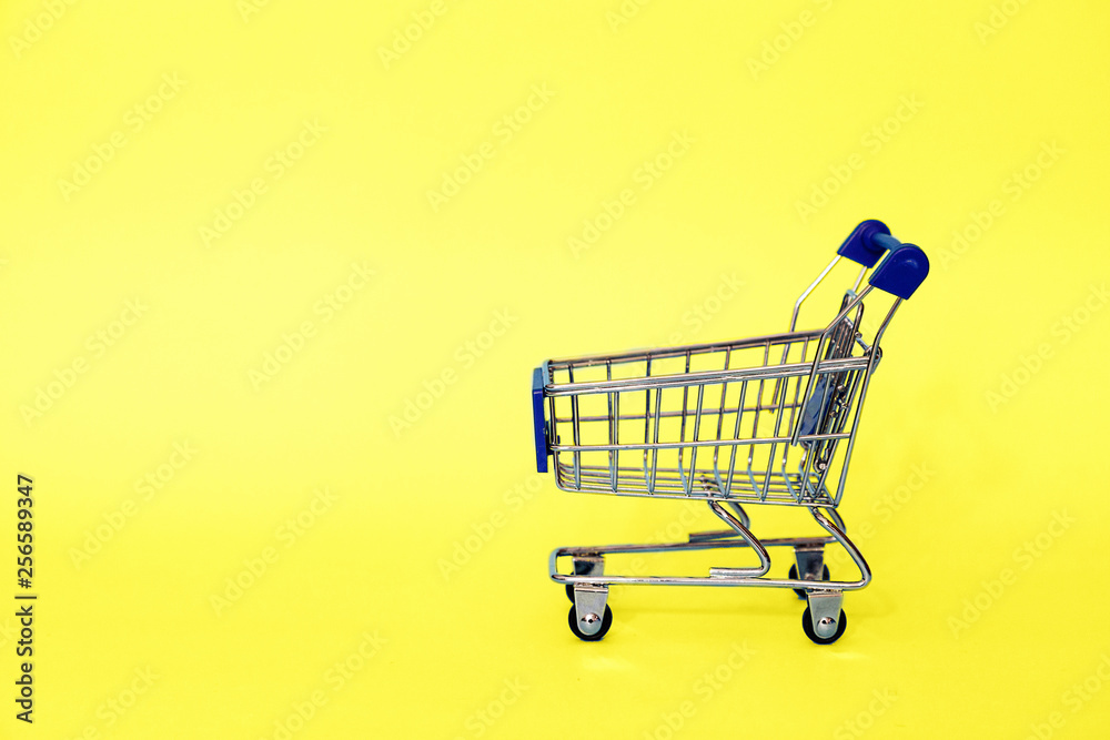 Grocery cart standing on yellow background. Place for text