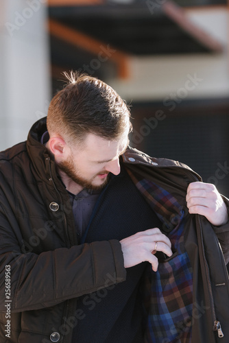 A man with a beard in a warm winter brown jacket poses for advertising of men's clothing in the winter. Advertising of men's clothing