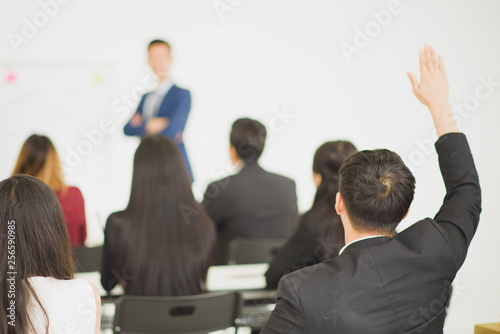 Young Asian people audiences seminar group raising up hand for asking the speaker that allow to raising up hand in question and answer time in meeting room see from back side of room.