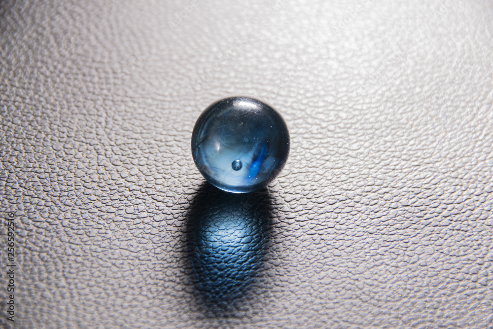 blue glass ball on black leather background blue glass ball on black leather background