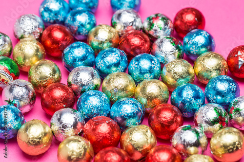 Chocolates in a multi-colored foil on a pink background