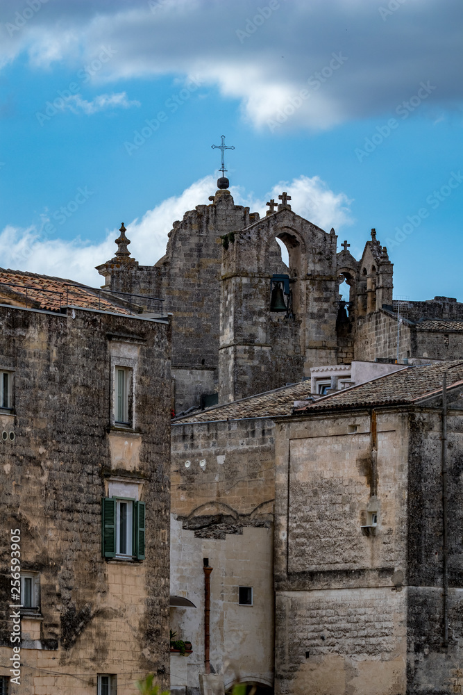 Summer blue sky and church roof with religious crosses, view of ancient town of Matera, the Sassi di Matera, Basilicata, Southern Italy, cloudy summer August day