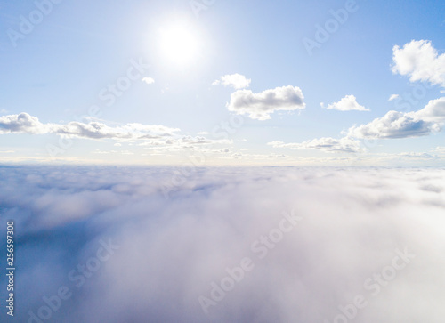 Aerial view White clouds in blue sky. Top view. View from drone. Aerial bird's eye view. Aerial top view cloudscape. Texture of clouds. View from above. Sunrise over clouds © Aleksei