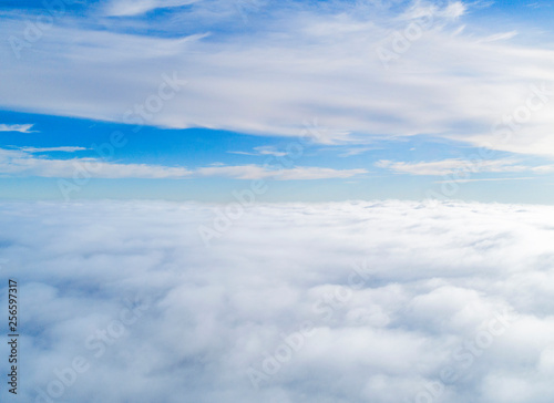 Aerial view White clouds in blue sky. Top view. View from drone. Aerial bird's eye view. Aerial top view cloudscape. Texture of clouds. View from above. Sunrise over clouds