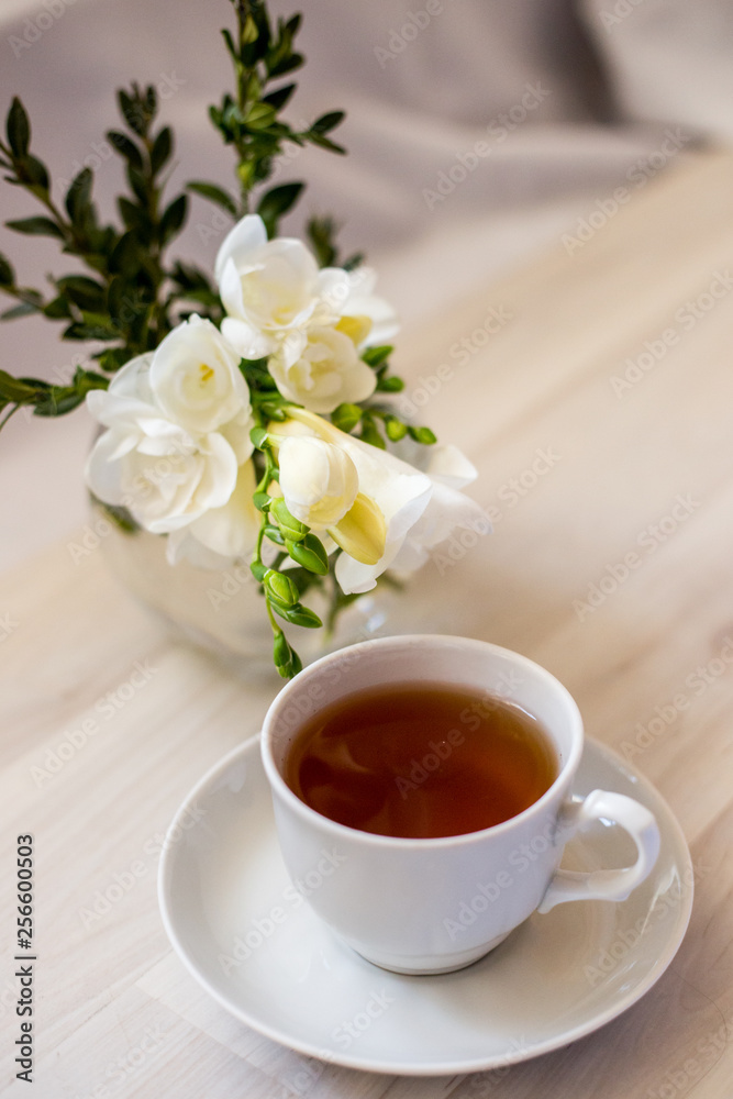 cup of tea and white freesia flower cup of tea and white freesia flower