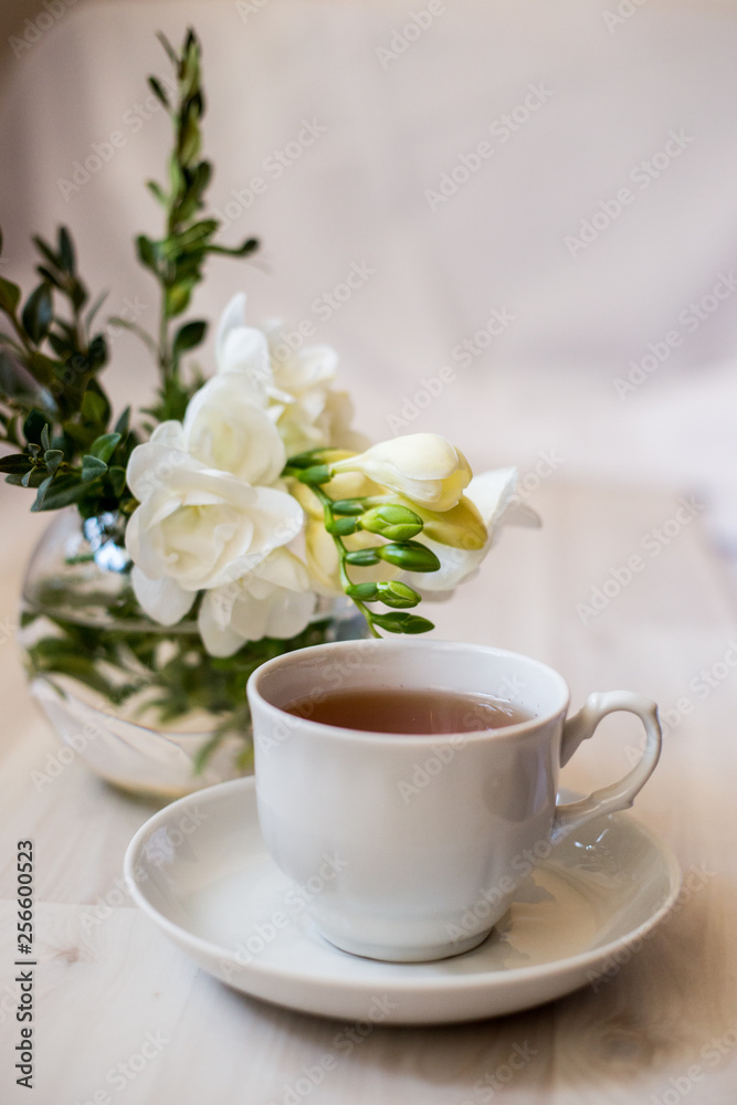 cup of tea and white freesia flower