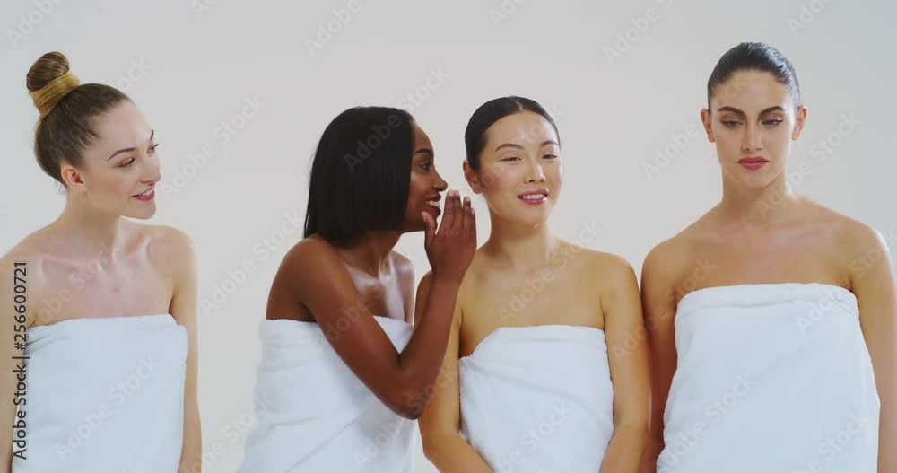 Slow motion of beautiful young smiling women of different ethnicities with perfect firm and slim body in white bathing towels whispering their beauty secrets in the ear and having fun. Slow motion of beautiful young smiling women of different ethnicities with perfect firm and slim body in white bathing towels whispering their beauty secrets in the ear and having fun.