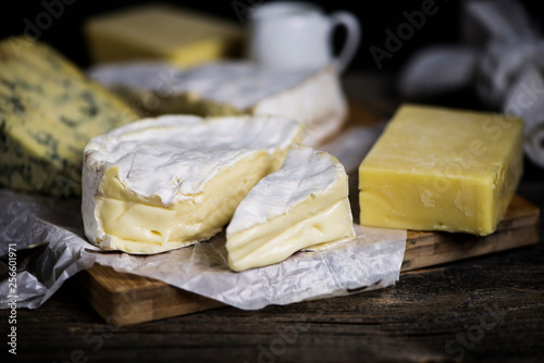 camembert cheese and a set of cheeses on a wooden board on a dark background
