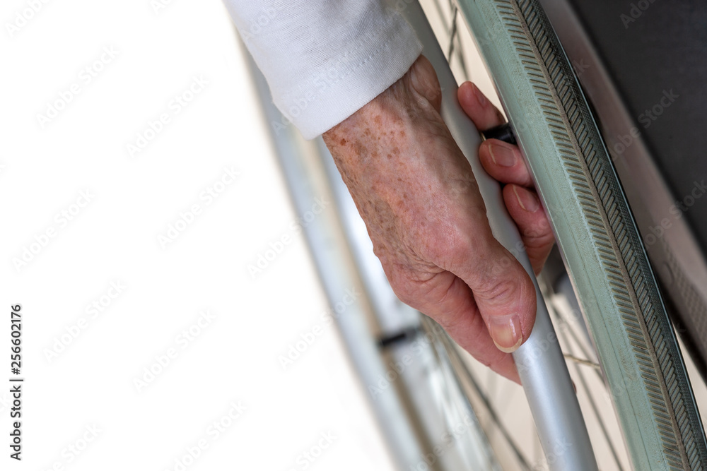 Obraz premium Closeup of senior hand turning wheels on his wheelchair, wheels on wheelchair
