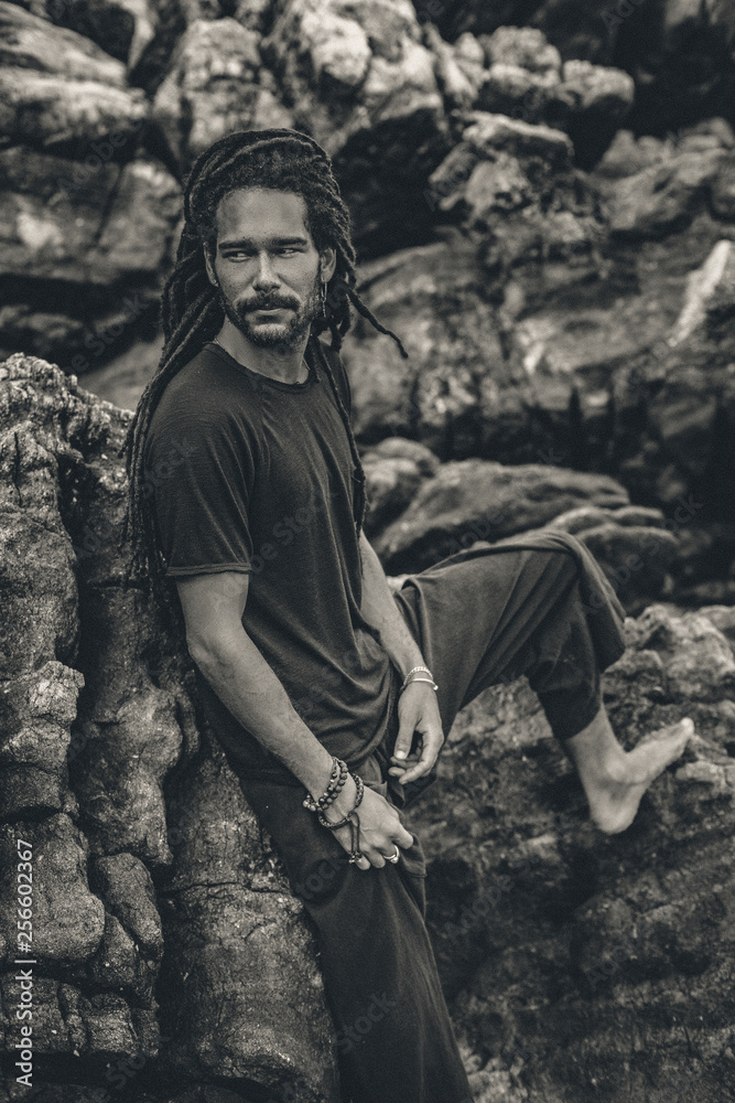 Handsome young man with dreadlocks outdoors. male model at the rocks Handsome young man with dreadlocks outdoors. male model at the rocks