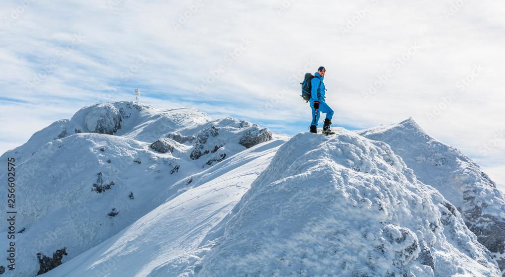 Hiker with winter equipment on the snow-ice ridge.