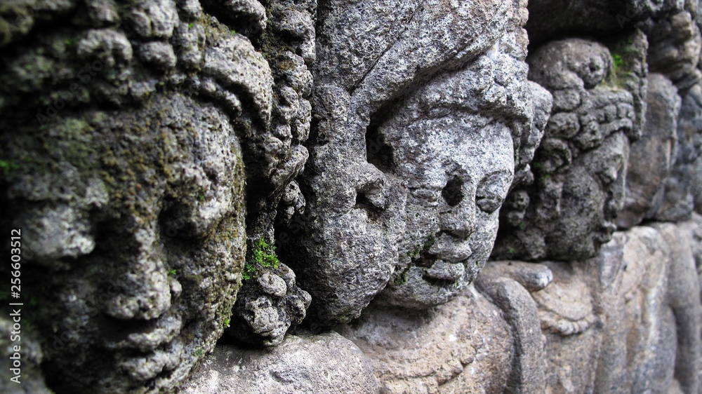 Ancient stone carving of women's faces in Borobudur, or Barabudur, world's largest Buddhist temple and a UNESCO World Heritage Site, located in Magelang, Central Java, Indonesia.