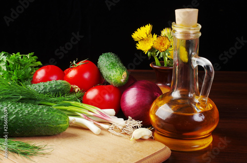 Fototapeta Naklejka Na Ścianę i Meble -  Vegetables for salad and a bottle of sunflower oil on a dark background