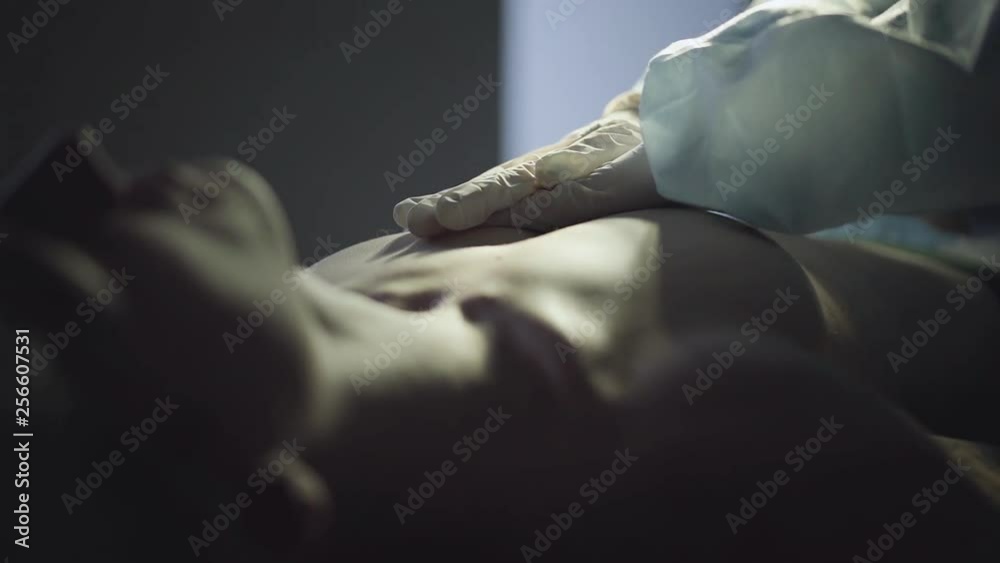 Doctors hands in white gloves making chest compression to a human body