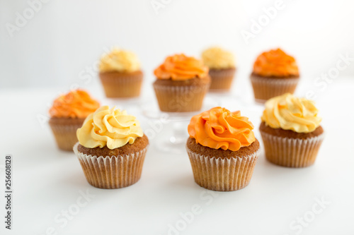 food, pastry and confectionery concept - cupcakes with buttercream frosting over white background
