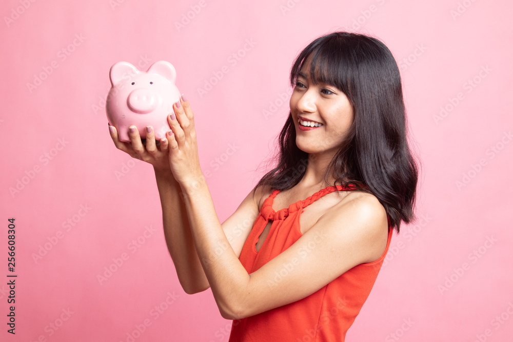 Young Asian woman with a pig coin bank. Young Asian woman with a pig coin bank.