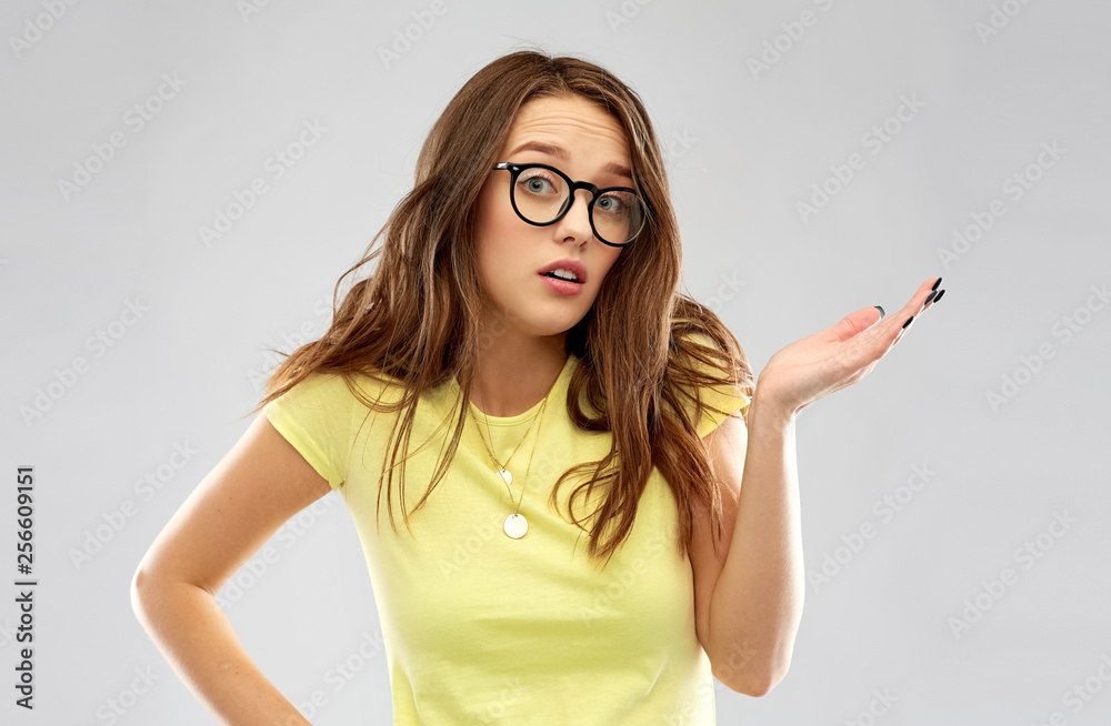 people, emotion and expression concept - young woman or teenage girl in yellow t-shirt and glasses shrugging over grey background people, emotion and expression concept - young woman or teenage girl in yellow t-shirt and glasses shrugging over grey background