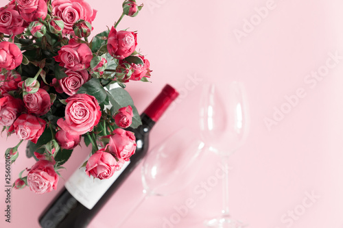 Pink rose flowers, wine and glasses for wine on pastel pink background. Valentine's Day. Birthday, Happy Women's Day. Flat lay, top view, copy space