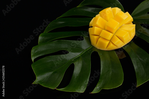 Photography Peeled Pineapple on plant leafs over black background