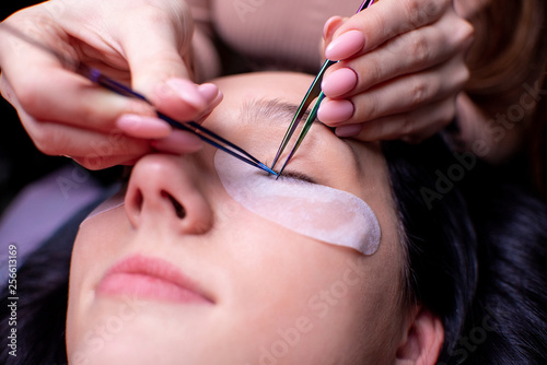 Beauty salon  eyelash extension procedure close up. Beautiful woman with long hair. Personal care