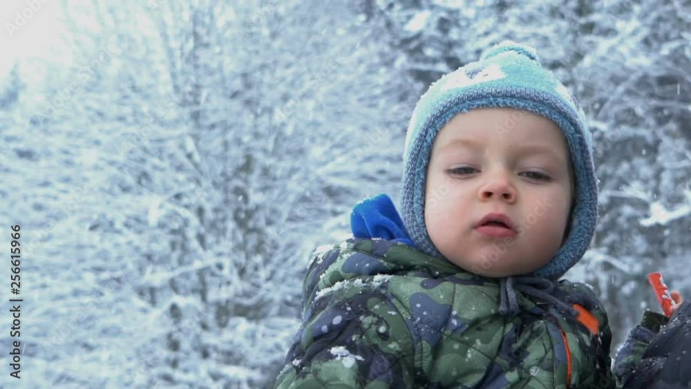 Pensive child with snow on face at winter landscape outdoors, slow motion