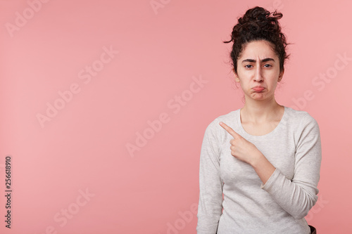 Photo of young woman standing isolated over pink background with copyspace for your advertising, points with one finger up, wears casual white longsleeve.