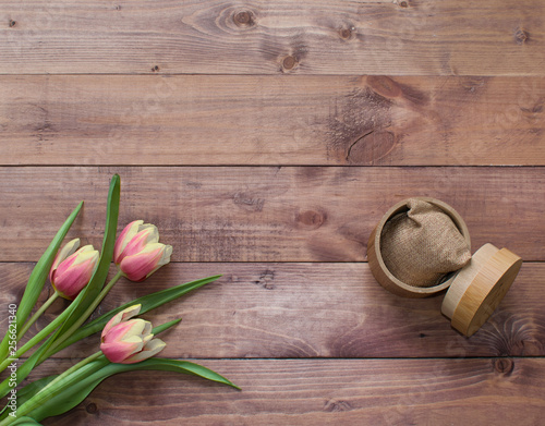 Flatlay Spring Easter bouquet of tulip flowers with wood box and linen sack on wooden background.View with copy space