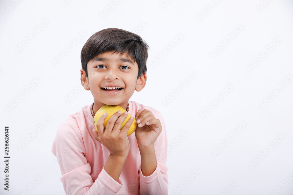 Cute indian/Asian little boy eating Mango with multiple expressions. isolated over white background Cute indian/Asian little boy eating Mango with multiple expressions. isolated over white background