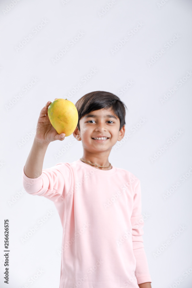 Cute indian/Asian little boy eating Mango with multiple expressions. isolated over white background Cute indian/Asian little boy eating Mango with multiple expressions. isolated over white background