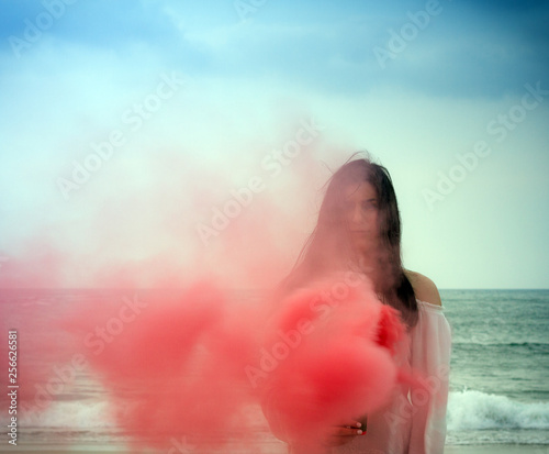 Chica en la playa con humo rojo en un dia soleado