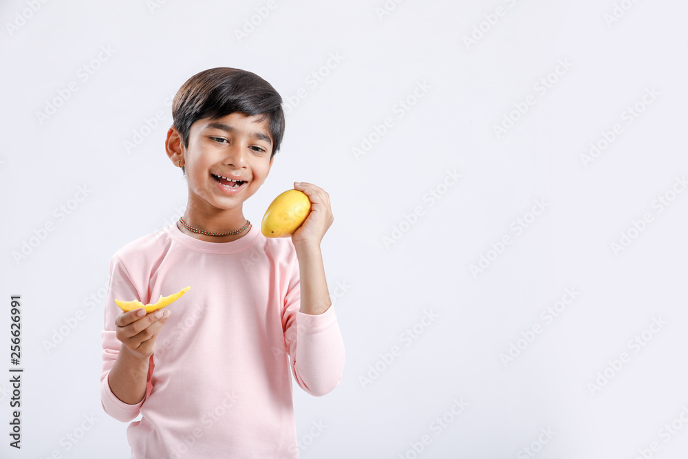 Cute indian/Asian little boy eating Mango with multiple expressions. isolated over white background Cute indian/Asian little boy eating Mango with multiple expressions. isolated over white background