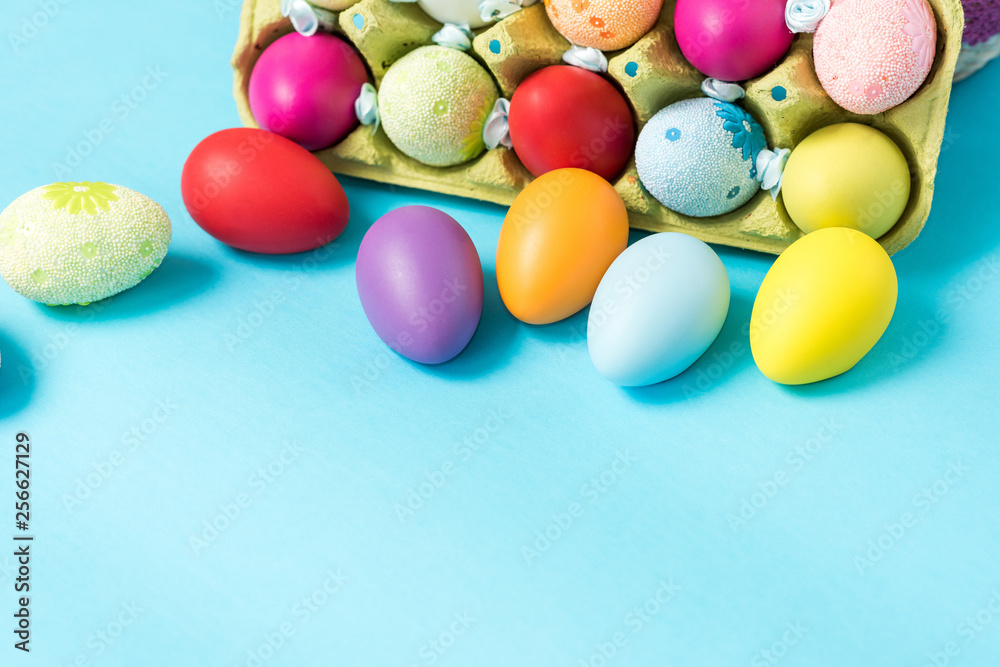 Easter eggs are painted in bright colors, lie in a cardboard eco-packaging. Blue background. Easter ideas. Space for text. Egg eco tray. Happy easter.