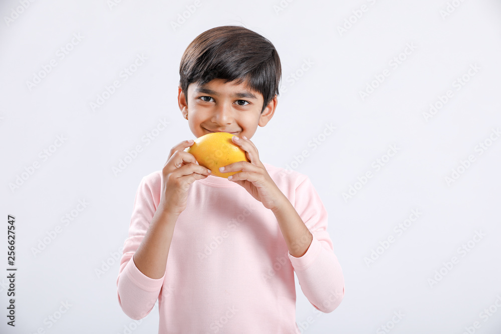 Cute indian/Asian little boy eating Mango with multiple expressions. isolated over white background Cute indian/Asian little boy eating Mango with multiple expressions. isolated over white background