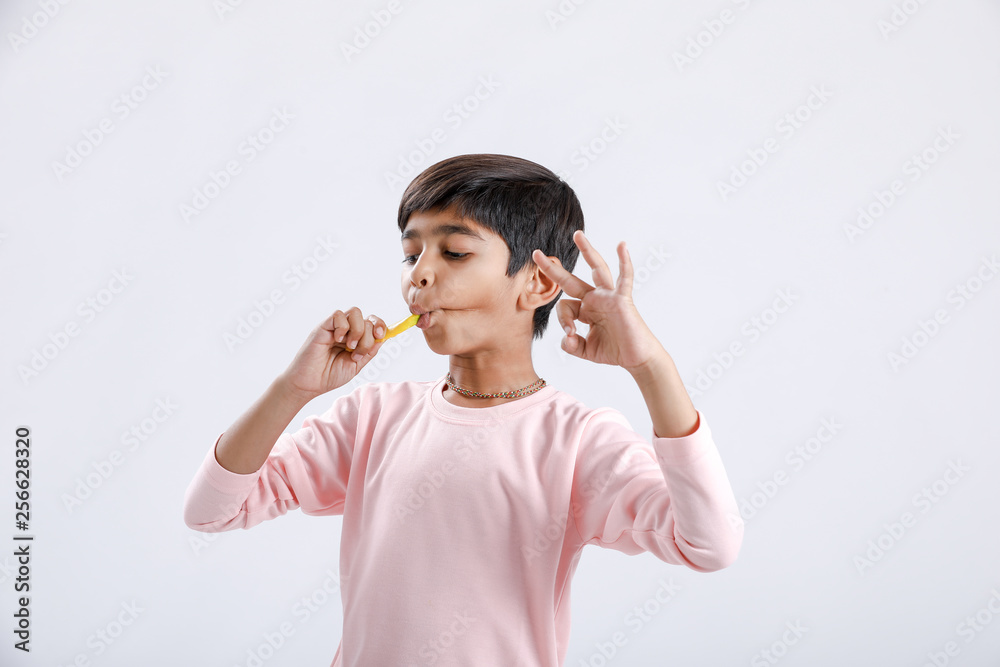 Cute indian/Asian little boy eating Mango with multiple expressions. isolated over white background Cute indian/Asian little boy eating Mango with multiple expressions. isolated over white background