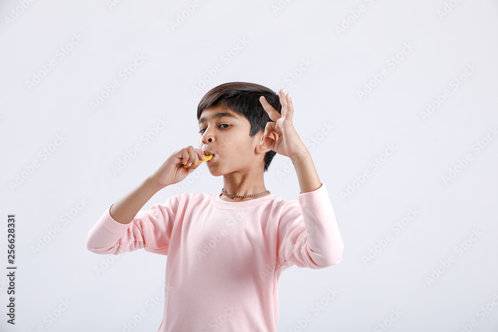 Cute indian/Asian little boy eating Mango with multiple expressions. isolated over white background Cute indian/Asian little boy eating Mango with multiple expressions. isolated over white background
