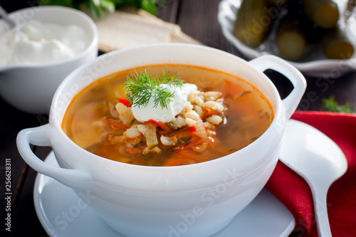 Soup with pickled cucumbers and pearl barley - rassolnik on a wooden background,horizontal