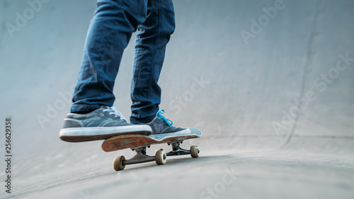 Urban skater practice. Man riding skateboard. Legs in jeans shot. Skate park ramp. Copy space. © golubovy