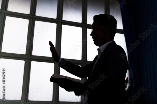 Fotografia Silhouette of pastor wearing suit with rectangular window frame