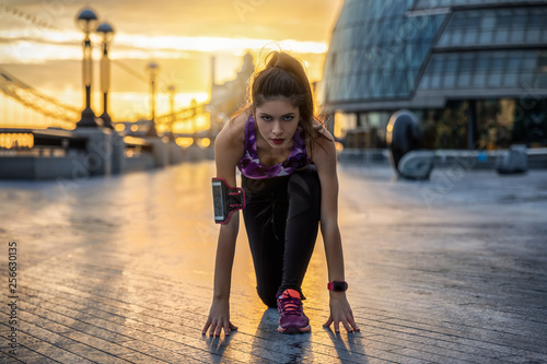 Sportliche Frau in Starter Position beim Training in der Stadt während Sonnenaufgang