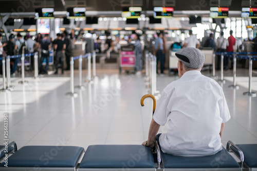 Elder man sitting in front of the check in counter waiting for his family