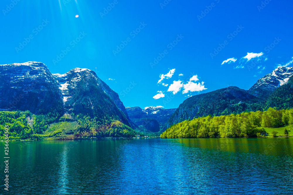 Mountain and amazing Alpine lakes, Hallstatt, Austria with blue sky and sun ray. Lens flare from the upper left corner