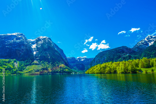 Mountain and amazing Alpine lakes, Hallstatt, Austria with blue sky and sun ray. Lens flare from the upper left corner