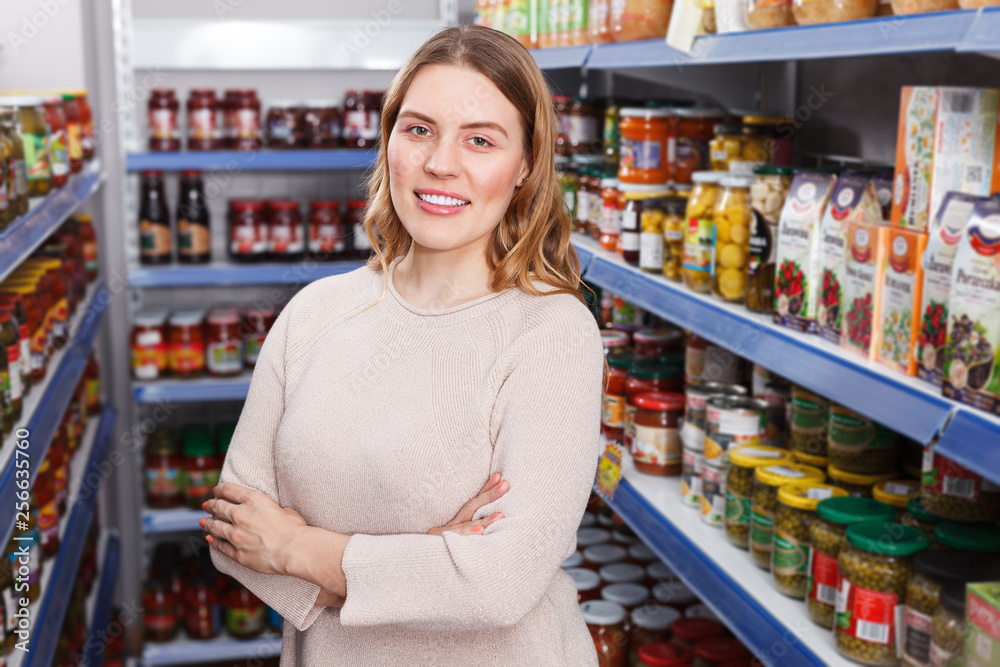 Portrait of positive female customer near shelves with pickle goods